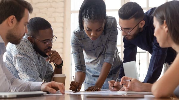 woman writing a document while men watch