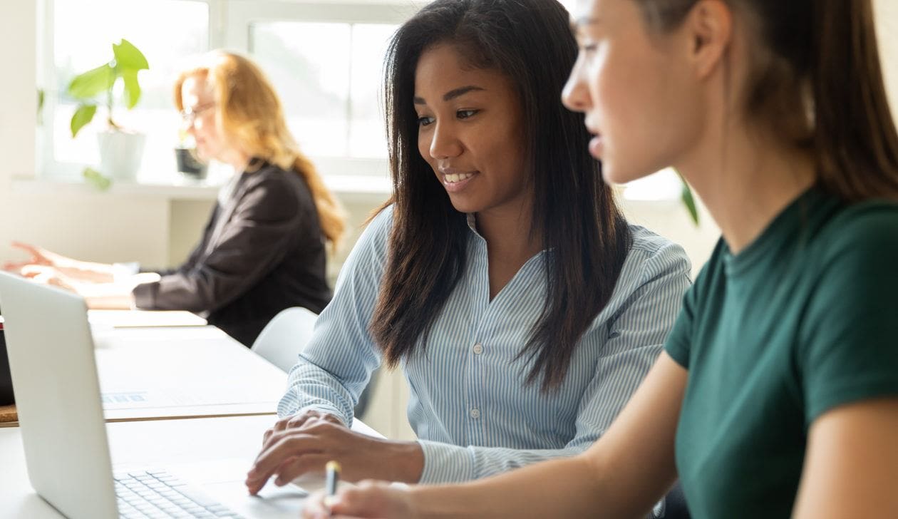 two women chatting by a computer