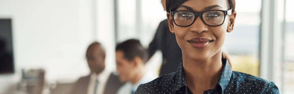 professional woman in glasses with colleagues in the background