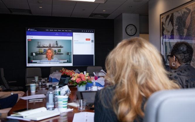 people in conference room watching large screen