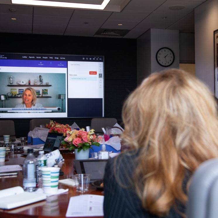 people in conference room watching large screen