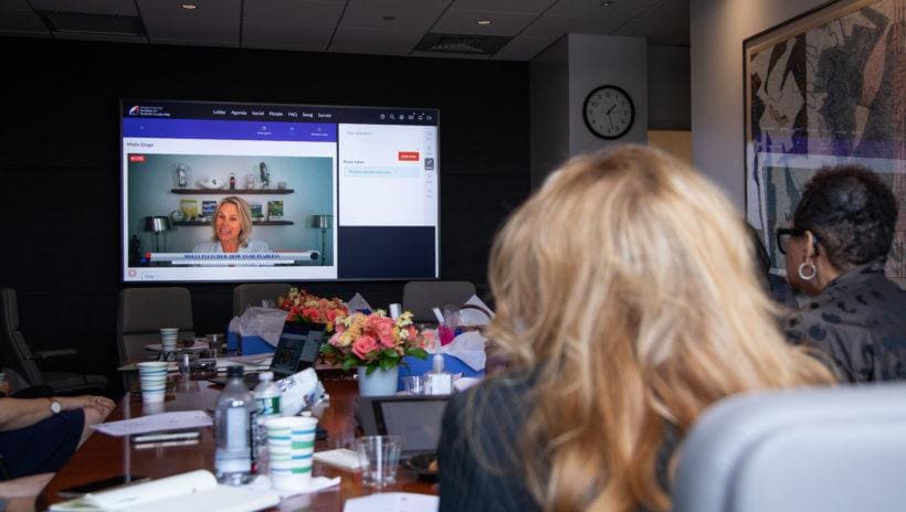 people in conference room watching large screen